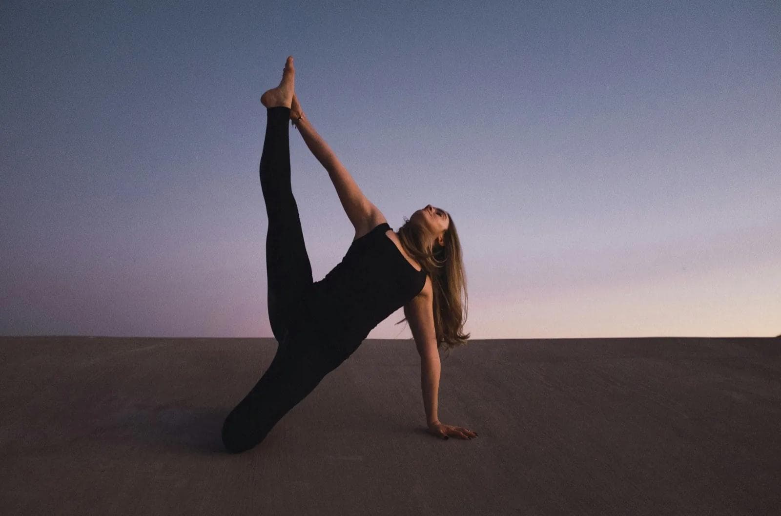 woman holding her left leg high kneeling on floor