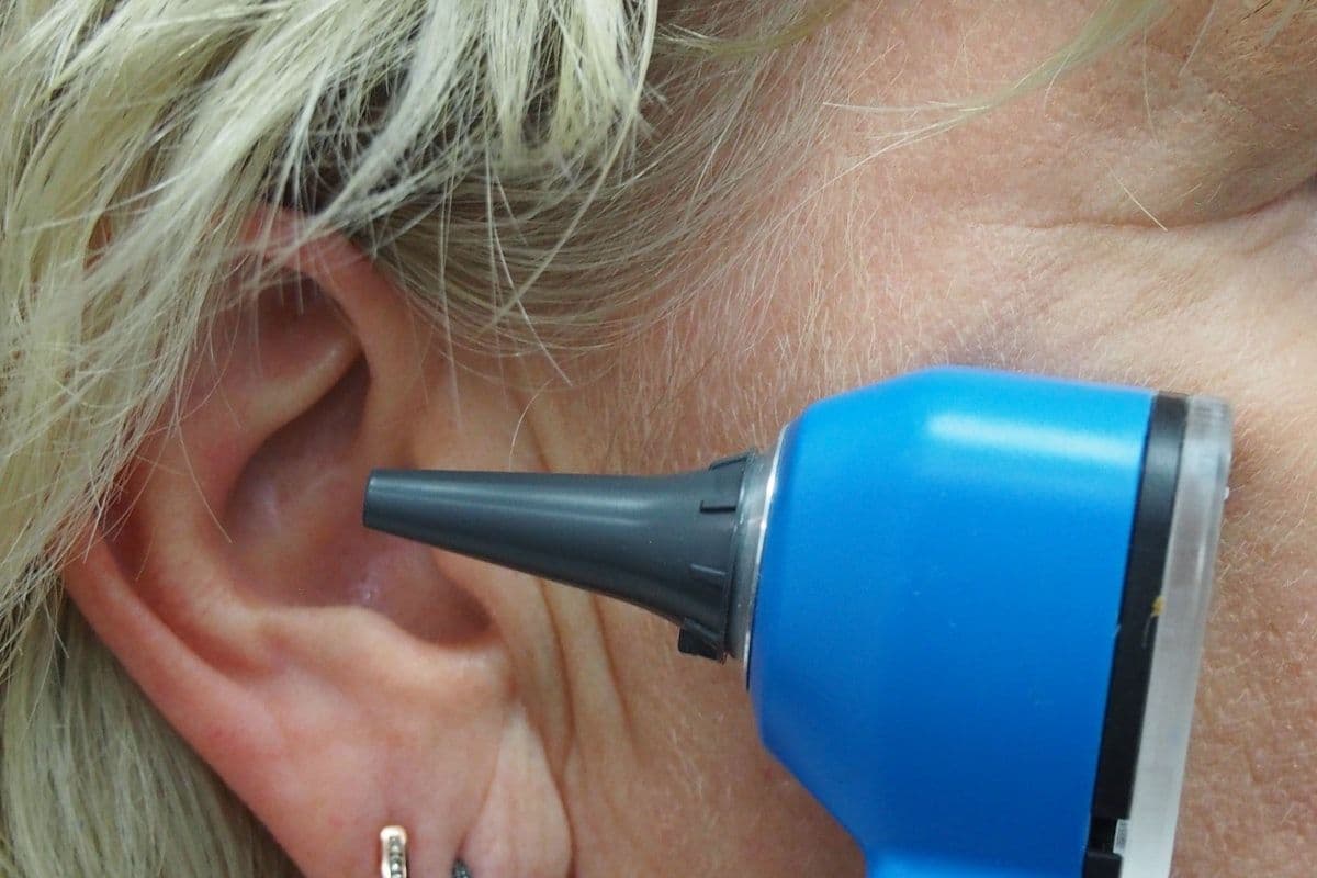 A clinician examining an ear with an otoscope