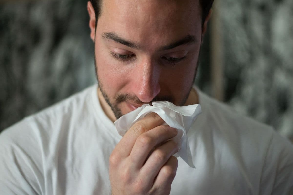 A man blowing his nose into a tissue