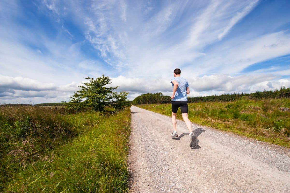 A man jogging along a path beside grass