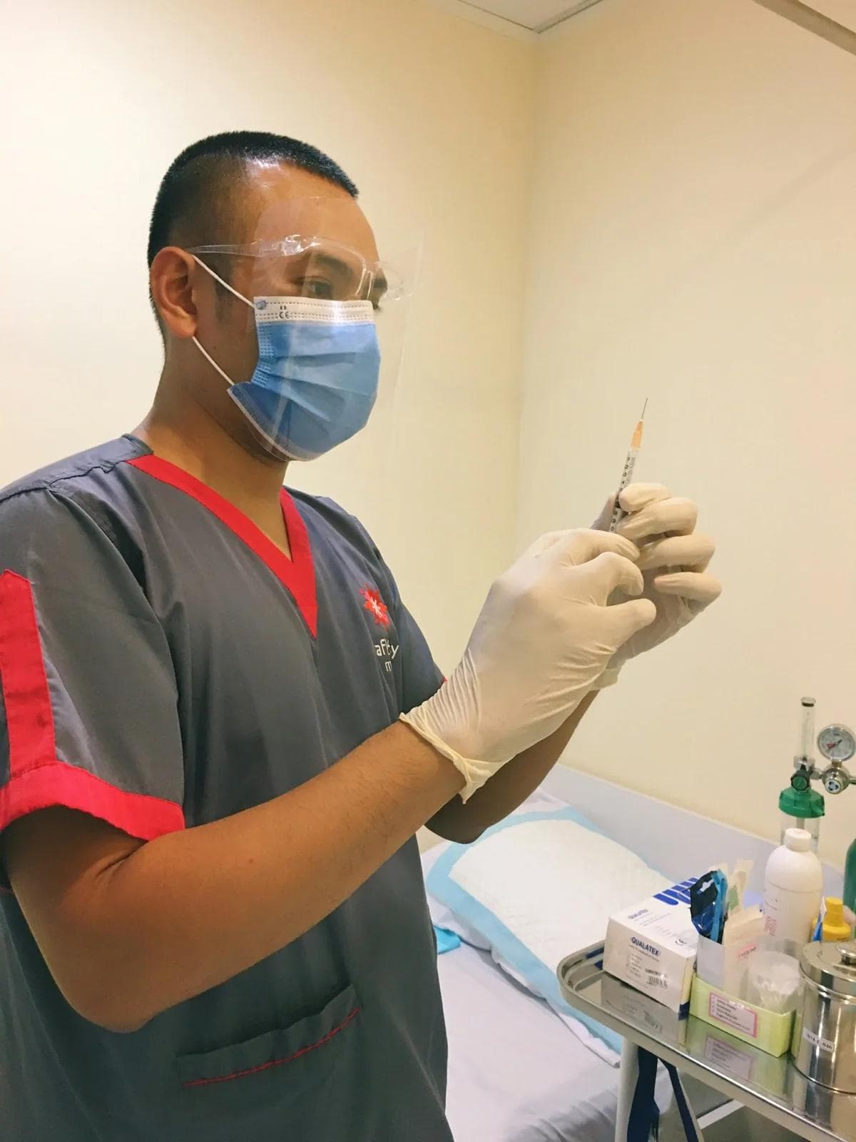 man in red and black crew neck t-shirt holding white syringe