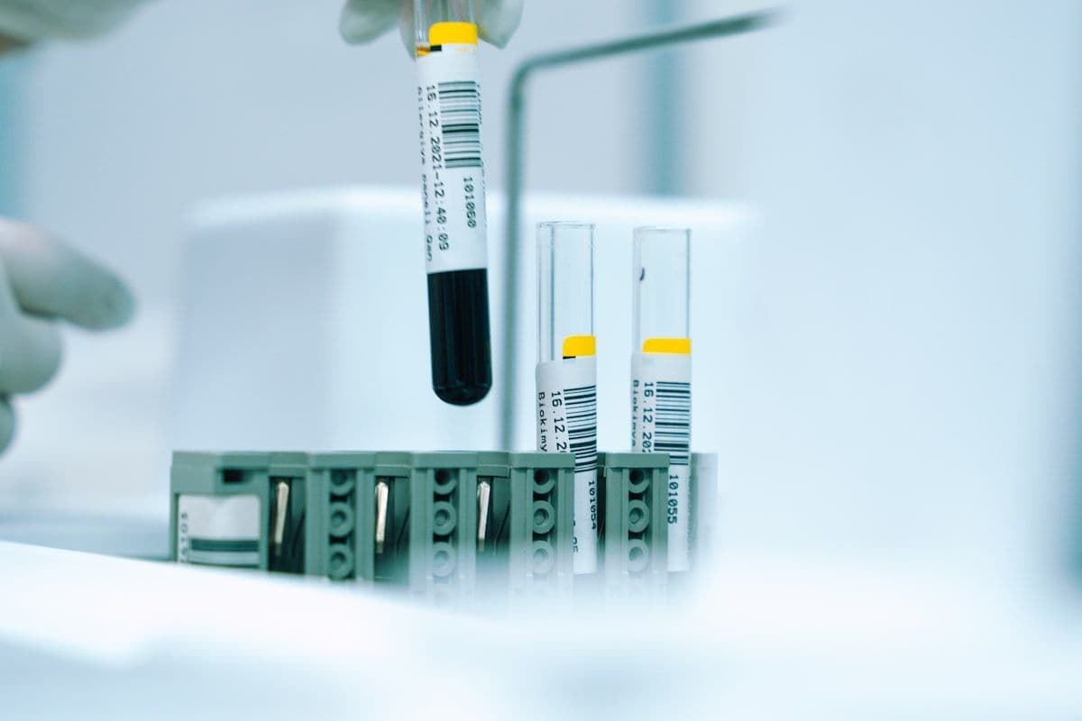 A gloved hand holding a single sample tube